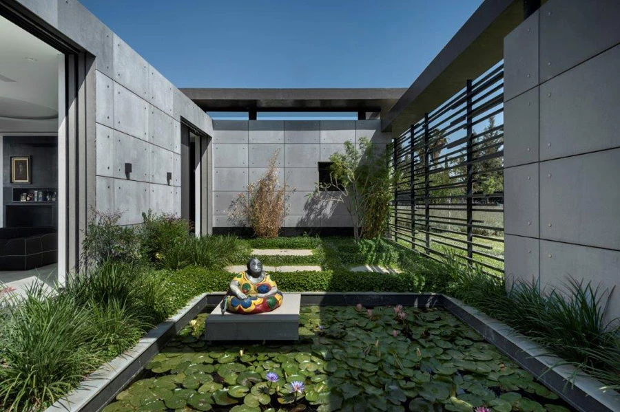 גן פנימי במרכזו גשר אבני מדרך שמוביל למבואת הכניסה הפנימית ומתחתיו בריכה אקולוגית | צילום: עודד סמדר | אדריכלים: דן והילה ישראלביץ