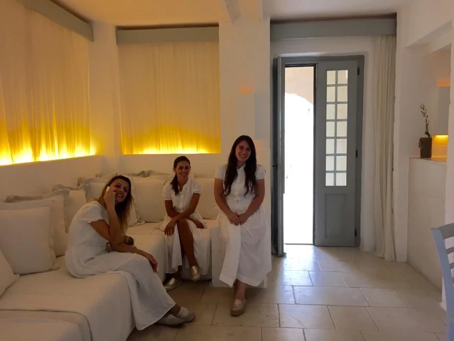 המארחת האישית שלנו יחד עם מארחות נוספות, לבושות שמלות פשתן לבנות. Credit: Ruth Arad