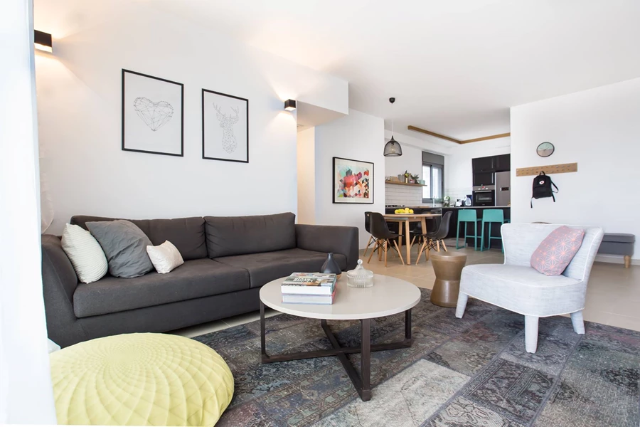 שטיח דומיננטי שמחבר את החלל יחד ועליו פוף של מיקה בר.