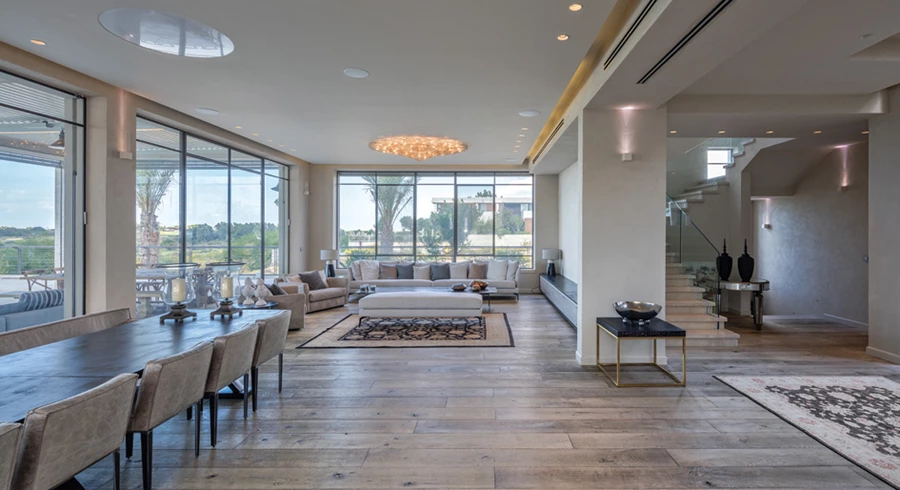 חלל המגורים: הפונקציות המשותפות ממוקמות לרוחבו ברצף, כך שכולן נהנות ישירות מנוף החוץ. פרופיל בלגי אפור כהה בפתחים, ריצוף פרקט אלון אפרפר בפלנקים רחבים מהמקובל, קירות בצביעת טיח אפור ותאורה מגוונת, צמודת קיר ותקרה בעיקר. גופי צמודי קיר: