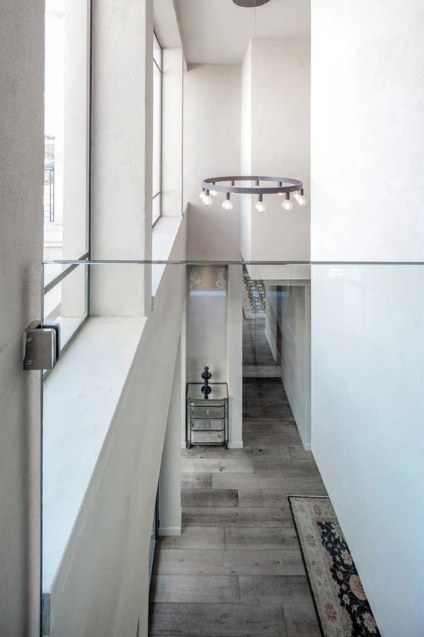 חלל המדרגות הפתוח שמוביל לקומה העליונה, מודגש באמצעות גוף תאורה גדול שנתלה ברום התקרה.  המדרגות עשויות אבן והמעקה השקוף נשתל בתוכן.