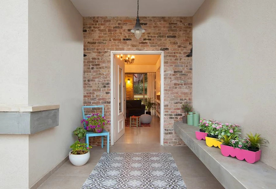ספסלי בטון ובריקים שיוצרים המשכיות בין הכניסה אל פנים הבית