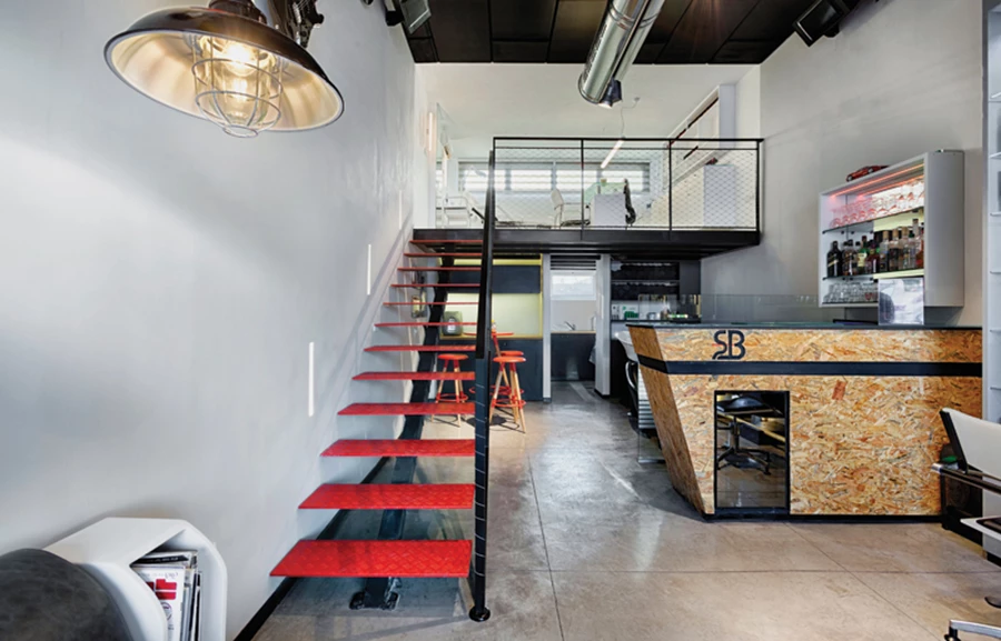 דלפק קבלה עשוי OSB בו משתלב מקרר יינות, וגרם המדרגות מדרגות הברזל המוביל 