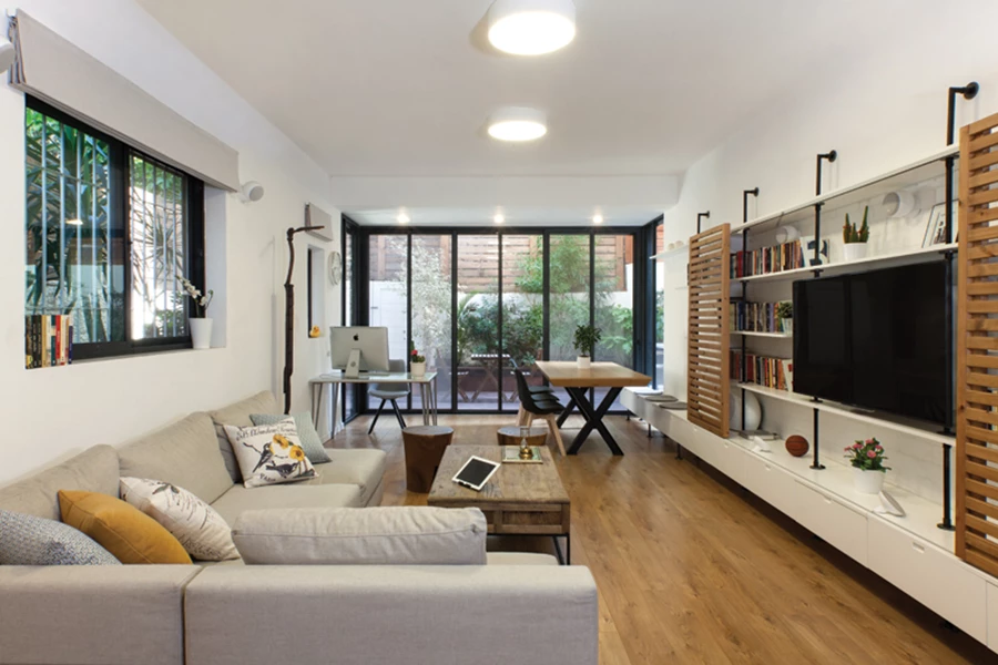 אזור הסלון/מגורים בדירה הגדולה לאחר העתקת מיקום השירותים: חלל פתוח המכיל פונקציות אירוח, פינת אוכל ופינת עבודה. ספרייה גדולה נמשכת לכל אורך הקיר, ויחידה מרחפת הממוקמת תחתיה הופכת בסופה לספסל ישיבה המשרת את פינת האוכל שבעומק החלל. תאורה: