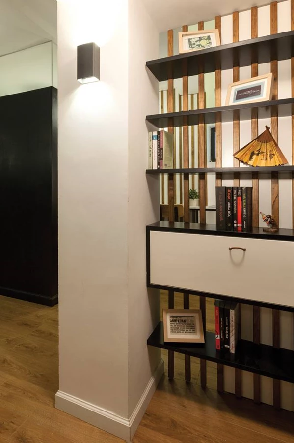 מבואת הכניסה לדירה הקטנה: ניצול עמוד קיים לתליית שידה ומדפים, אשר המרווחים ביניהם מעניקים הצצה למטבחון שמאחור.