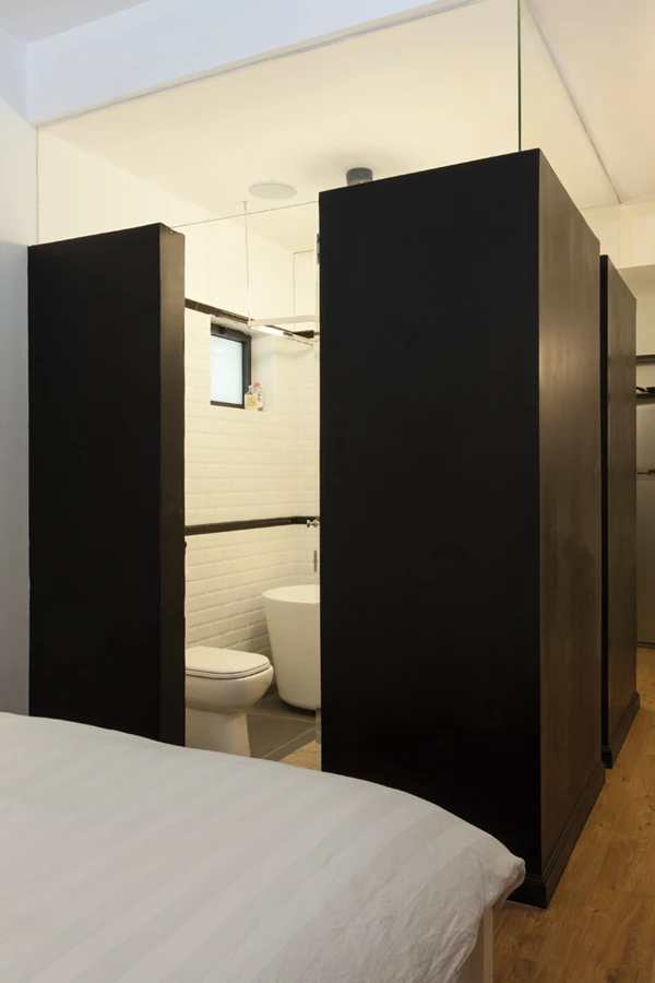 מבט לחדר הרחצה: קירותיו הצבועים בשחור אינם נמשכים עד התקרה, ובחלקם העליון מותקנות מחיצות זכוכית ששקיפותה מייצרת רצף עם תקרת הדירה כולה ומקנה ממד של פתיחות והמשכיות.הגון השחור מגדיר את חללו