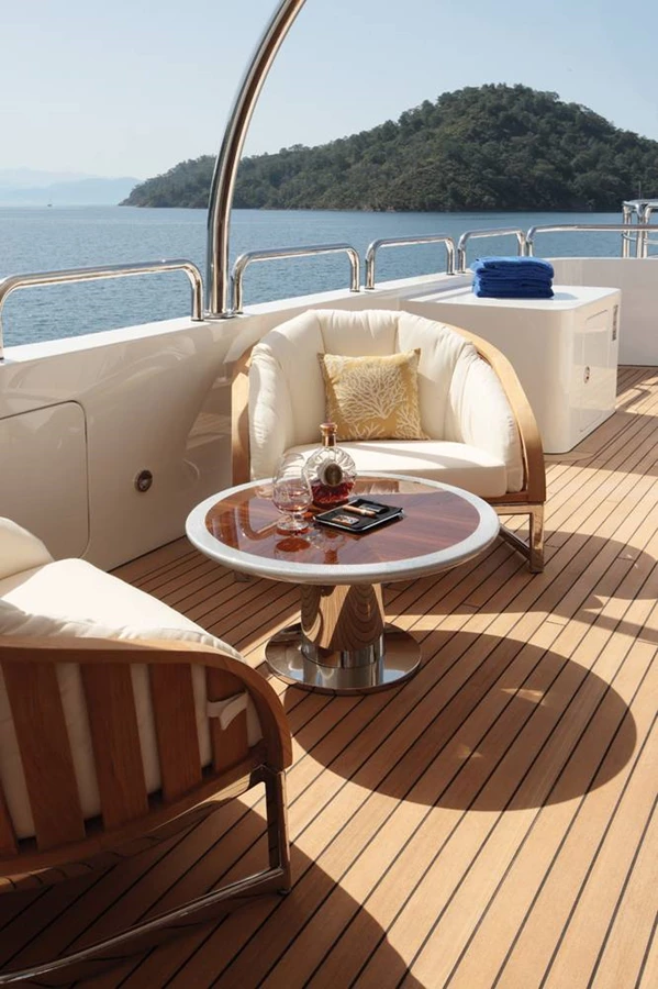 על אחד הסיפונים, שולחן שעוצב ייעודית כחלק מקולקציית הפריטים שהוזמנה: בסיס נירוסטה, משטח עץ טיק בציפוי אפוקסי מבריק עמיד במיוחד בפני קרינת UV ותנאי סביבה ימית,  ו