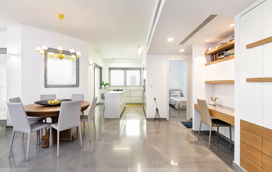 מבט מהכניסה: פינת העבודה הממוקמת לצדה, פינת האוכל הממוקמת מולה, והכניסה למטבח. ארון חשמל שניצב לצד פינת העבודה מעוצב בהתאמה אליה ליצירת רצף ויזואלי המטמיע אותם בחלל. ביצוע: יפרח בן צבי.