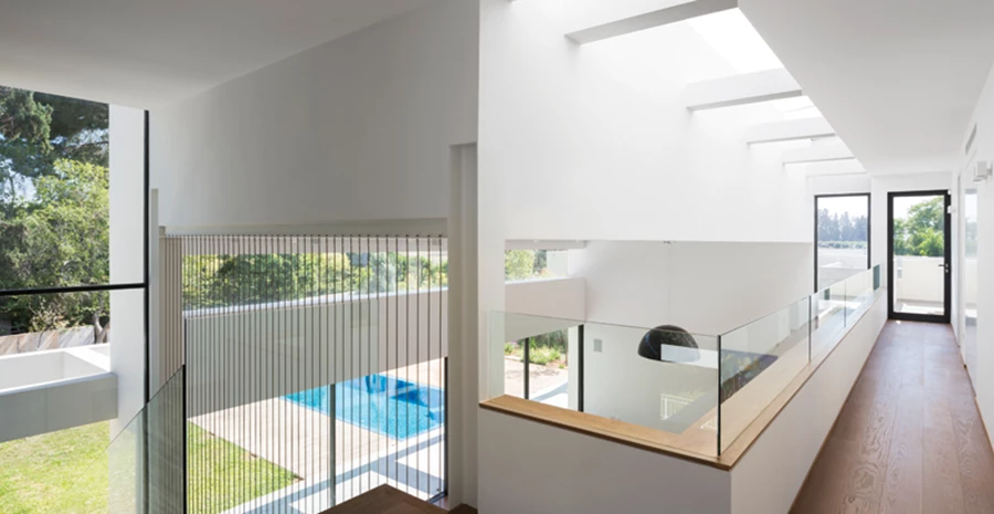 הגלריה שבקומה העליונה: ריצוף פרקט ומעקה בנוי נמוך משולב עם זכוכית שקופה המעניקה קשרי עין ישירים עם החלל הנפרש תחתיה.