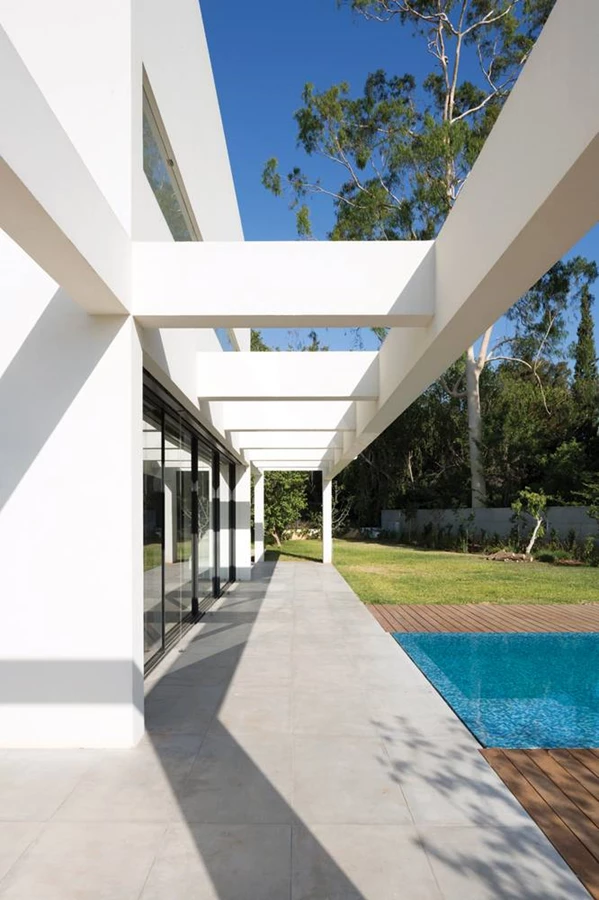 ביציאה מחלל המגורים: בחזית האחורית מתנתקת קורת הפלדה ממסת המבנה והופכת לפרגולה המקרה רחבת מרוצפת.