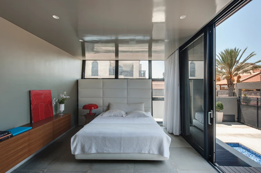 יחידת ההורים בקומת הקרקע של הגוש הנמוך נהנית מחצר פרטית משלה, ובכלל זה משטח דק לשהייה אינטימית בחוץ. עיצוב מינימליסטי הנקשר לאדריכלות: גב מיטה מרופד וגבוה מהמקובל שתוכנן ככזה בהתאמה למיקומו של קיר חיצוני המשתלב במעטפת.