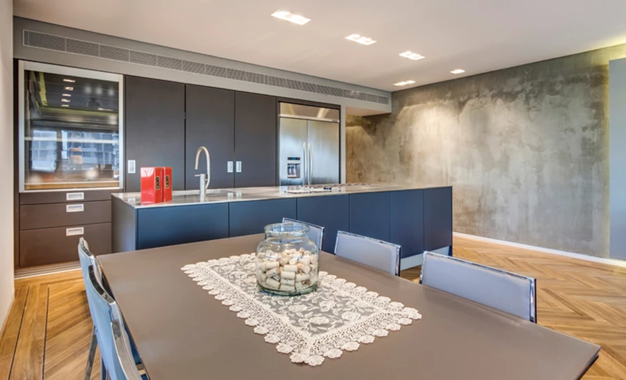 המטבח: יחידת אי ויחידת קיר עם חזיתות באפורות כהה בגימור צבע בתנור. במשטח הנירוסטה של יחידת האי משתלבים כיור, כיריים וקולט אדים נשלף, חזיתות ההזזה של יחידת הקיר ניתנות לסגירה מלאה, ולחלופין להסטה החושפת משטח עבודה נוסף המוצנע בתוכה. פינת האוכל בעיצוב מודרני תואם למטבח: שולחן בקווים נקיים-מינימליסטיים וכיסאות עם בסיס נירוסטה. מטבח: ׳האקר׳.