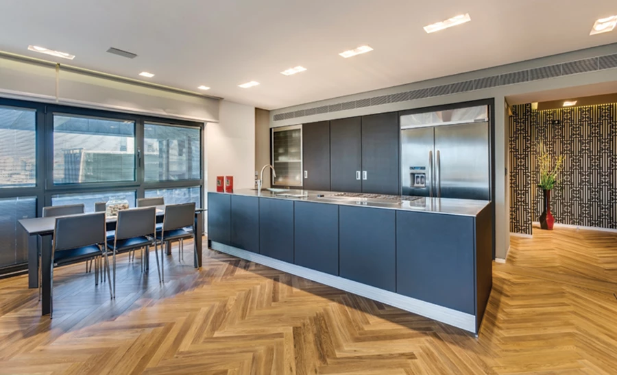 מבט מאזור המבואה לאזור המטבח ופינת האוכל שבקדמת החלל. חיפוי קיר בטפט שמהדהד תצורת משרבייה.