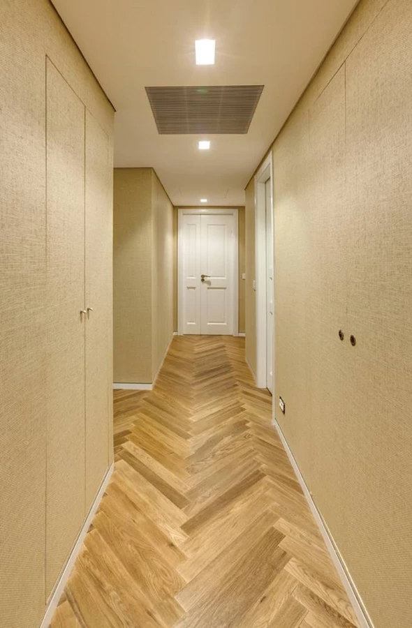 מעבר החדרים באגף הפרטי. פנלים נסוגים מקו הקיר מקנים ממד אוורירי לחלל הצר.