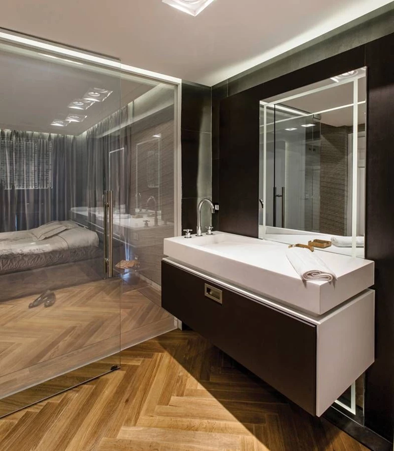 חדר הרחצה: חיפוי קיר בפלטות גרניט פורצלן שחורות וגדולות במיוחד, יחידות כיור מרחפות עם משטחי קוריאן, ושתי מראות גדולות מרצפה לתקרה שכמו חוצות אותן מאחור. מאחורי הקיר וממסגרות המראות מופצת תאורה נסתרת, ודיגום המשרביה של הטפט בכניסה מצוטט בתוך גומחה על זכוכית מודפסת בשילוב תאורה. אביזרים סניטריים: MODY.