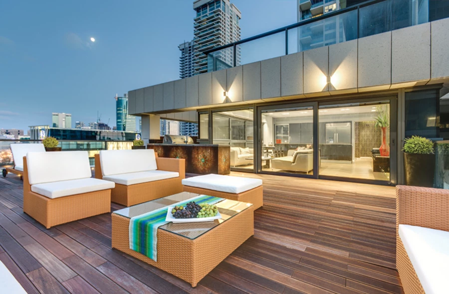 המרפסת ביציאה מהחלל הציבורי: ריצוף דק עץ, אזורי ישיבה שונים, ומטבח מאובזר לעילא שמאפשר לארח בנוחות מול הנוף.