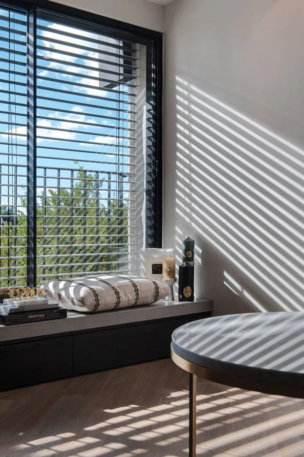 קרני שמש החודרות מבעד תריסי צלונים משרטטות בחלל דיגום פסים החובר למופעו הגראפי-גיאומטרי.