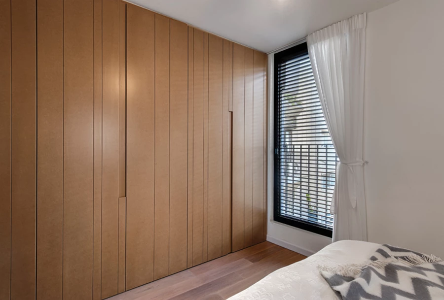 בחדר השינה: חזיתות הארון עשויות MDF בטקסטורת פסים אנכיים.
