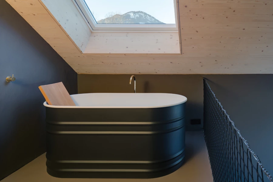 בשטח הגלריה שבמפלס העליון: אמבט פרי סטנדינג אובאלי בטעם של פעם, וסקיילייט בתקרת העץ שמעליו.