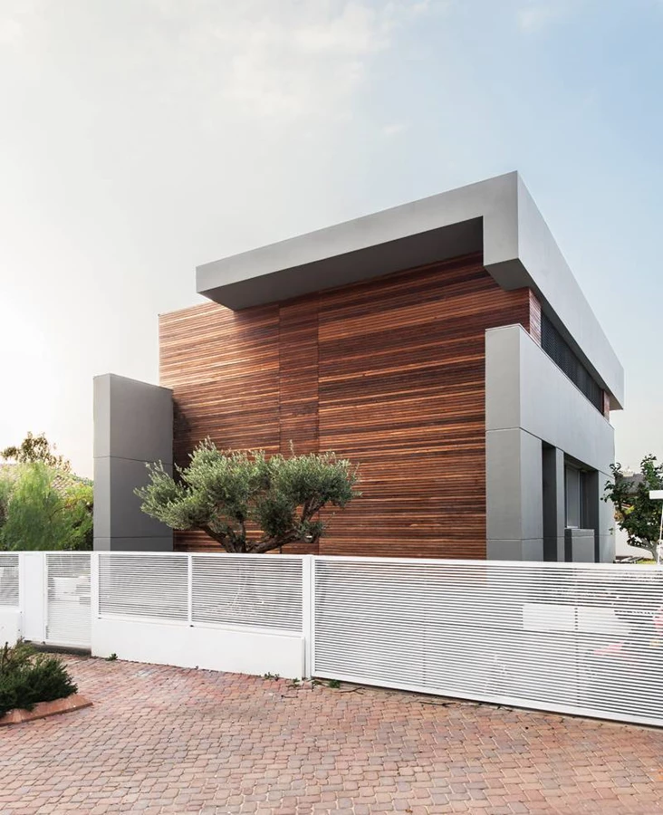 החזית הקדמית: חיפוי בסרגלי עץ איפאה בהתקנה סמויה ומסגרת בטון העוטפת את המבנה ב