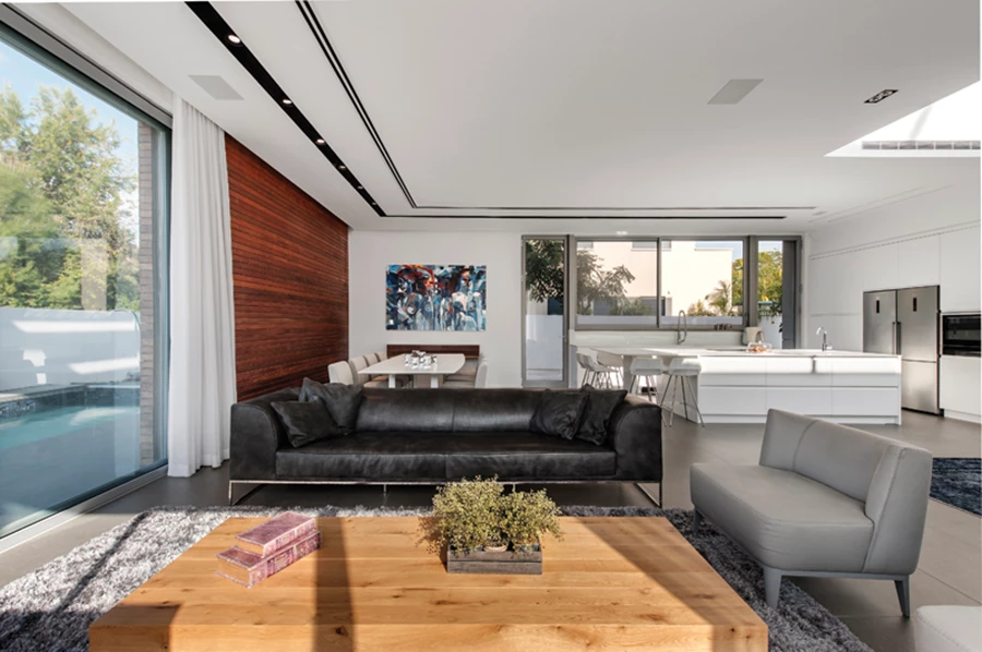 קשרי חוץ-פנים: פינת הישיבה מוצבת כך שהיא פונה לנוף הגינה שנחשפת מבעד לויטרינות גדולות.