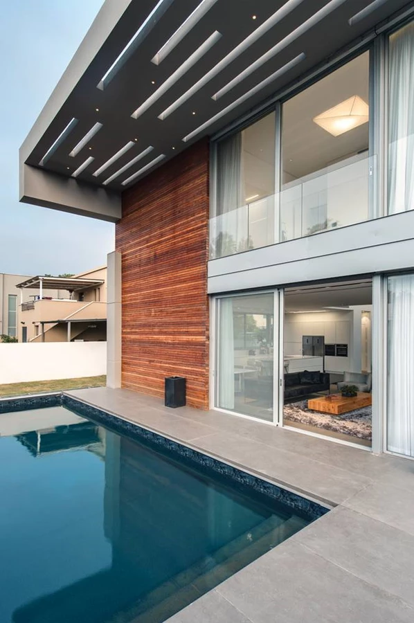 מסגרת הבטון של החזית הקדמית ממשיכה לחזית האחורית בה היא הופכת לפרגולה בנויה, ואף חיפוי העץ זוכה ל