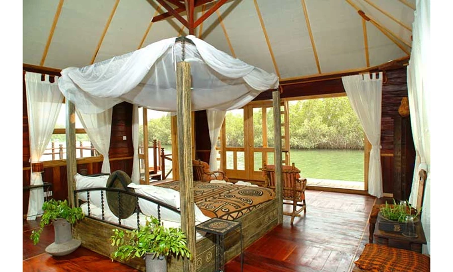 Credit:The Gambia Experiance החדר עם המיטה במרכז והנוף הפתוח לנהר, פרטי ריהוט אפריקאים