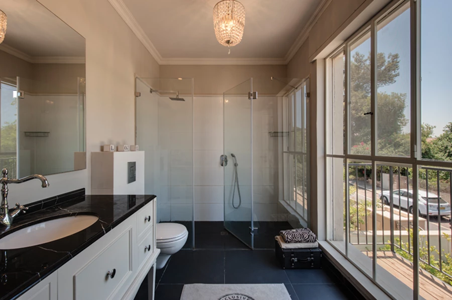 שילובי גון שחור בחדר הרחצה של יחידת ההורים:  ריצוף באריחי גרניט פורצלן, משטח שיש ביחידת הכיור, וגוף תאורה מעוצב כעין אשכול קריסטלים שנוסך ממד אלגנטי- עתיק.