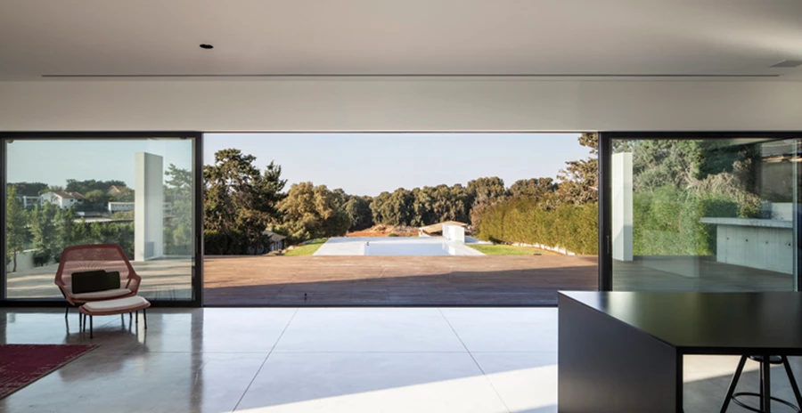 רצף ויטרינות במסגרות אלומיניום שחורות מייצר בחלל הציבורי חזית שקופה הנמשכת מקצה לקצה וחושפת את מלוא מראות החוץ. פתחים: