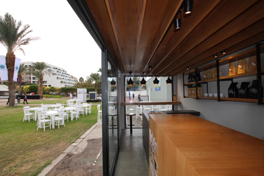 ריצפת העץ המקורית של הקונטיינר חופתה בלוחות צמנט להשלמת המראה המודרני של בית הקפה.