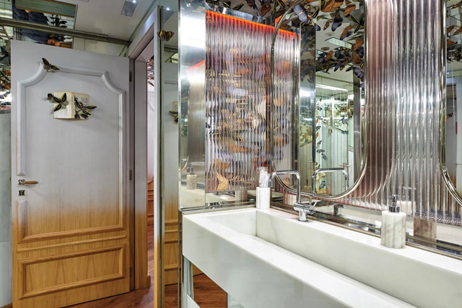 חלל השירותים: ריצוף שיש, ספרים ופרפרים כחיפוי קירות, אסלות ורודות ומראות המייצרות סוג של תעתוע המהדהד את אליסה בארץ הפלאות.