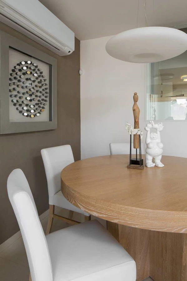 פינת האוכל, הממוקמת כמו מאחוריו גרם המדרגות: שולחן עץ עגול