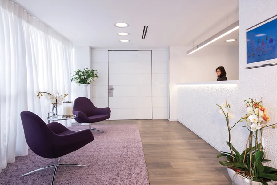 דלפק קבלה ופינת ישיבה מזמינה במבואת הכניסה לחלל. חיפויו הייחודי של הדלפק הלבן בוצע בחיתוך CNC, והוא ממשיך ומחפה גם את הקיר הסמוך הניצב אליו. שטיח: