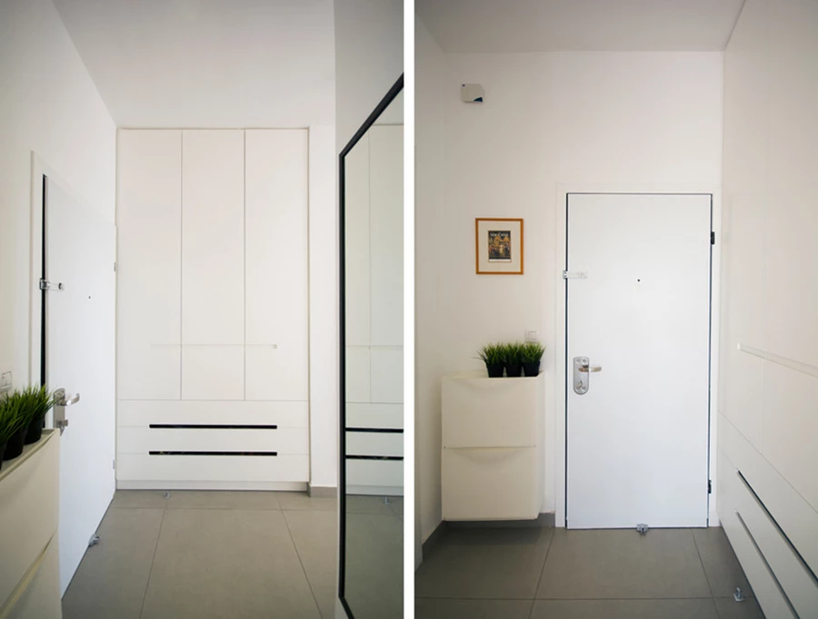 מבואת הדירה. ארון הכניסה כולל מגירות תחתונות לאחסון נעליים מאוורר, ומקום למעילים ותיקים למעלה. דלת הכניסה לא הוחלפה משיקולי תקציב אלא צופתה מחדש בוינוריט לבן והפרזול הוחלף. מראה גבוהה נתלתה מול הדלת.