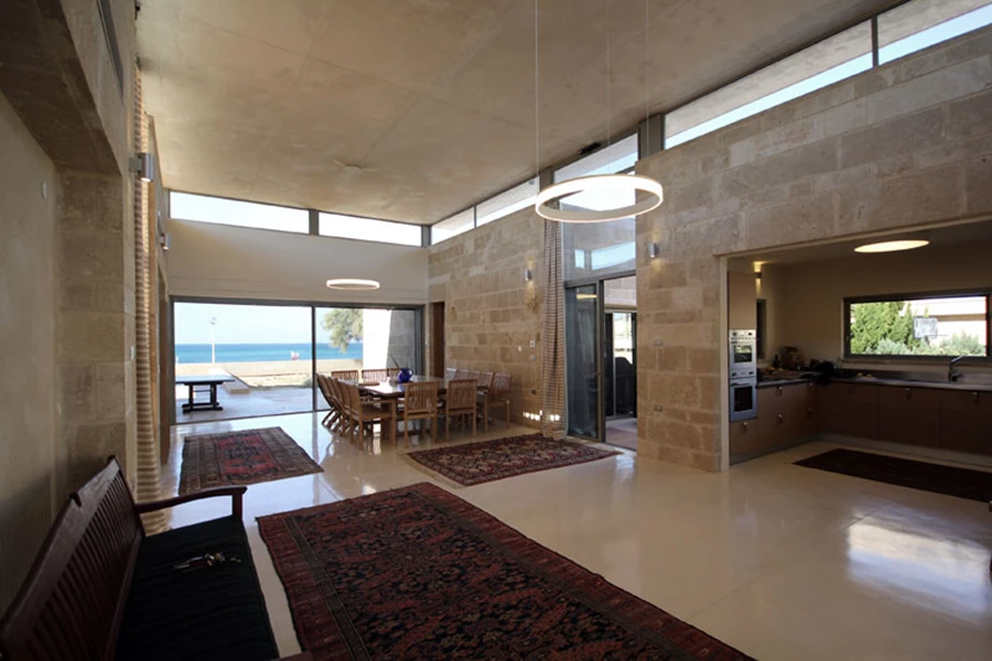 מבט מהכניסה אל החלל המשותף סביבו מאוגדות ארבע היחידות הבנויות: שקיפות, פתיחות וממד של ריחוף שמאציל הגג. מימין נראה המטבח, ובהמשך לו פרק החיבור השקוף עם היחידה הסמוכה אליו.