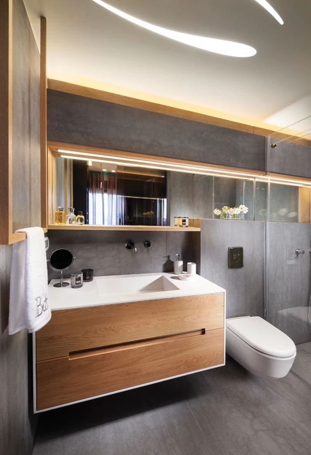 חדר הרחצה:  ריצוף וחיפוי באריחי גרניט פורצלן אפורים במראה טיח, ופריטי נגרות מעץ טבעי משתלבים עם אלמנטים מבניים- עיבוי שנדרש להתקנת הניאגרה חובר למדף שמעל הכיור וממשיך וחודר למקלחון תוך יצירת מראה שלם. אף מתלה המגבות עוצב ייעודית בהתאמה. מקלחון: