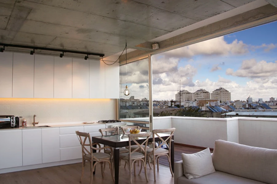 המטבח שבחלל הציבורי: חזיתות צבע בתנור וחיפוי קיר באריחים בעבודת יד בסקלה של גווני לבן. הדיגומים הרפטטיביים שמופיעים עליהם שונים אלה מאלה, אך משתלבים אלה עם אלה לכדי מופע מעודן וחי.