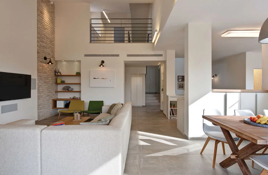 מבט מעומק חלל המגורים: האזורים השונים ממוקמים בנוחות נגישה משני עבריו של ציר מעבר ומעל נשקף מרחב פתוח בקומה העליונה.