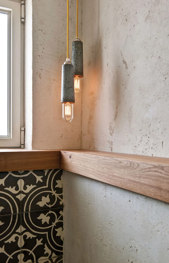 שירותי האורחים שהורחבו במסגרת השיפוץ:  שילוב של חיפוי קיר בטיח וגה במראה בטון ואריחים בטון מצוירים. גוף תאורה אף הוא מבטון של המעצב יואב וספי.