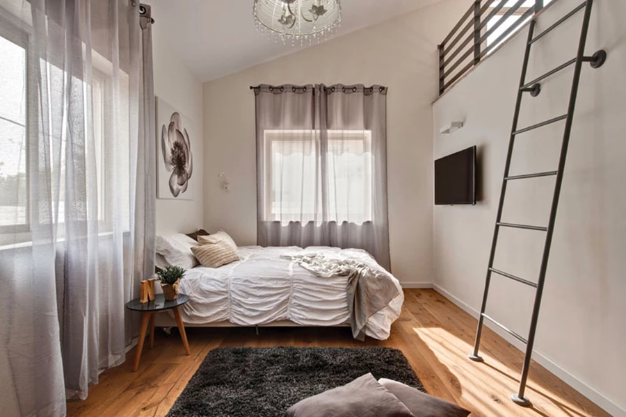 אחד מחדרי הילדים שבמפלס הביניים: מעוצב בקפידה עם טקסטילים רכים, וגובה התקרה מנוצל ליצירת גלריה עליונה עם סולם כאמצעי גישה אליה.