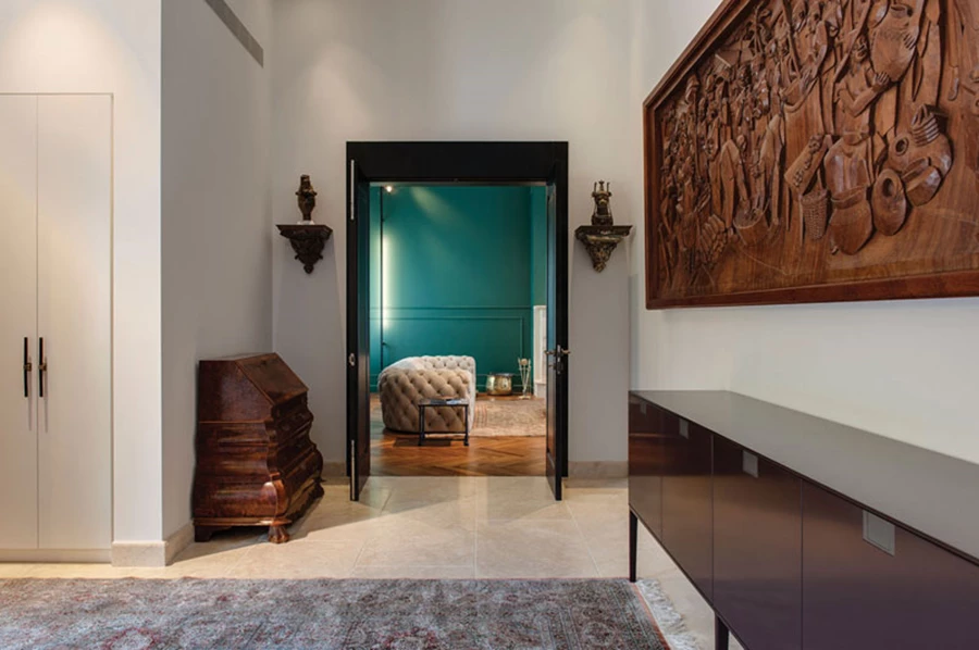 מבט מהמבואה לכיוון הסלון: דלת כנפיים עשויה אלון פרח שחור שסוגרת על פתחו מתבררת בהמשך כאחד ממאפייני הבית.