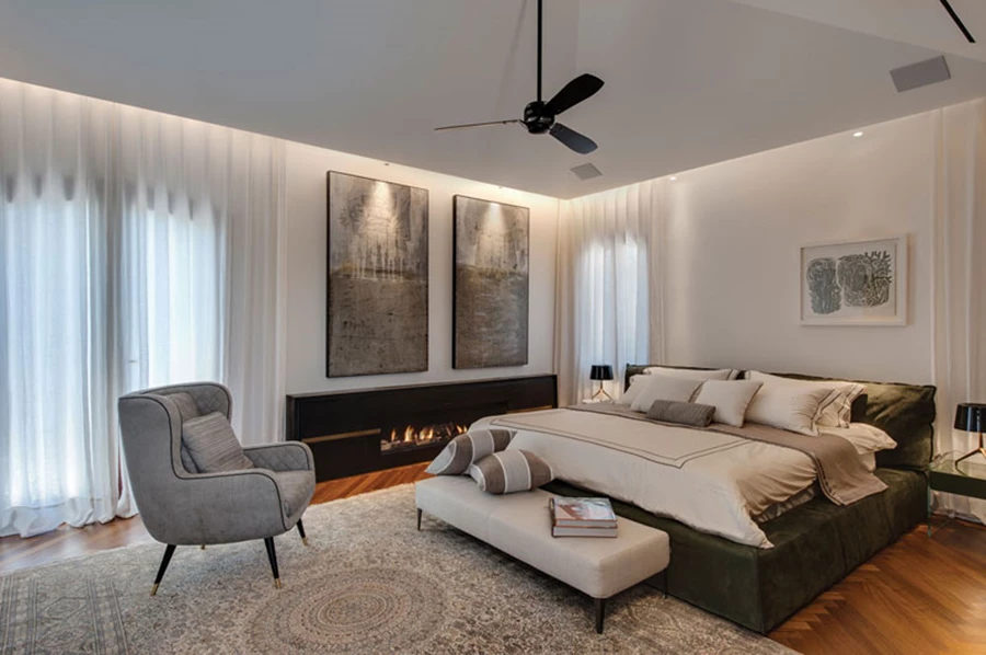 מול המיטה: קיר פאנלים צבוע בגון אפור אטום שמצניע בתוכו דלתות כניסה לאזורי הארונות והרחצה המצויים מאחוריו, ובמרכזו מותקן מסך הטלוויזיה. הדלתות נטולות הידיות נפתחות בלחיצה בלבד. פתח יציאה למרפסת מעוטר בוילונות אווריריים, בדומה לכל פתחי הבית האחרים. חלונות ודלתות: אפקס.