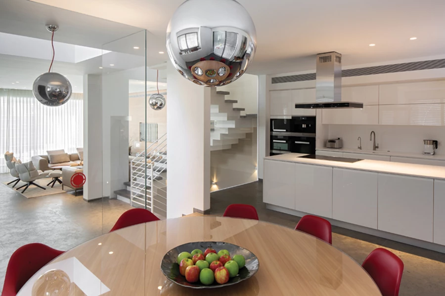 מבט מהמטבח אל עבר גרם המדרגות: מדרגות מנותקות ומחיצות שקופות מייצרות מראה אוורירי.