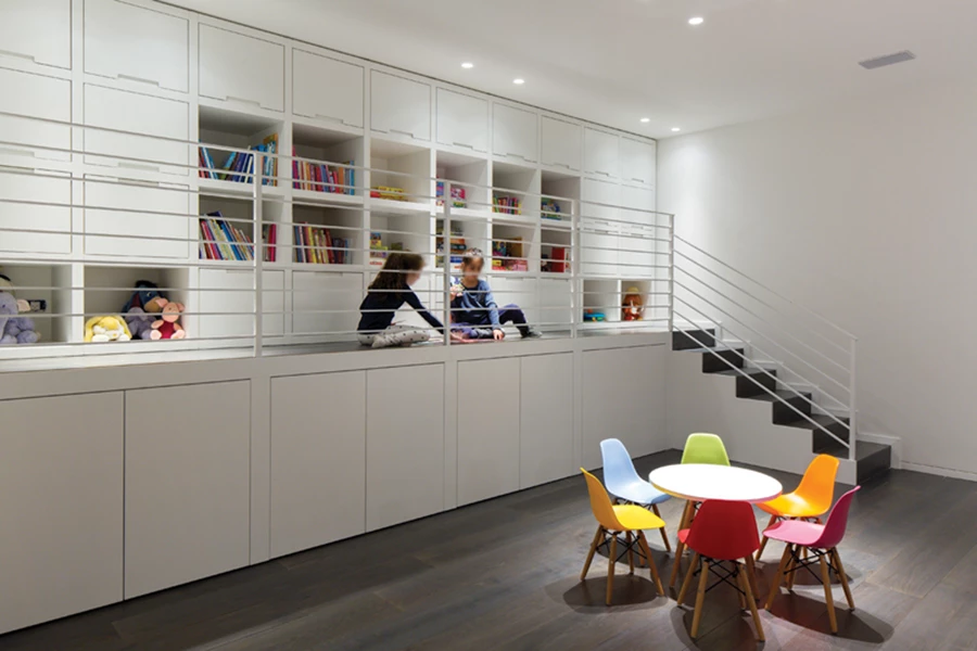 חלל מחלל המרתף מעוצב כבמה גבוהה תחומה במעקה הכוללת מדפי אחסון לצעצועים וספרים, מרחב ישיבה לצורך משחק, ואף מהווה אלמנט משחקי בפני עצמו. חלקה התחתון של הבמה משמש לאחסון צעצועים גדולים בעלי גלגלים, ושולחן קטן עם כיסאות צבעוניים משלים את אפשרויות הפעילות- לציור למשל. נגרות: הדר הן.