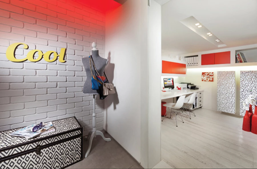 חדר העבודה: מעוצב על טהרת גווני אדום ולבן. | באזור המבואה שבמפלס הכניסה: קיר מחופה לבני סיליקט עם תאורה סמויה שמפיצה אור אדום מעליו, ומניקין חינני.