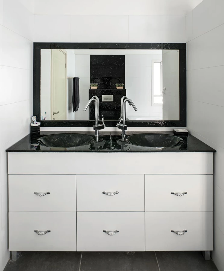 חדר הרחצה והשירותים ביחידת ההורים: משטח כיור+ כיור וחיפוי קיר בעבודת זכוכית של בעל הבית.