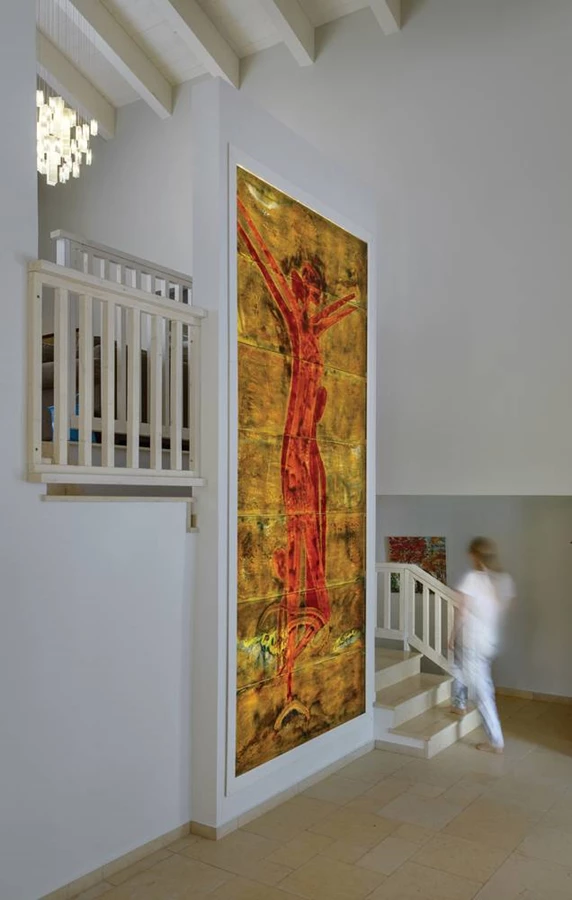 ציור קיר גדול בצבעוניות חמימה שבמרכזו דמות אישה מחבקת. הציור ה