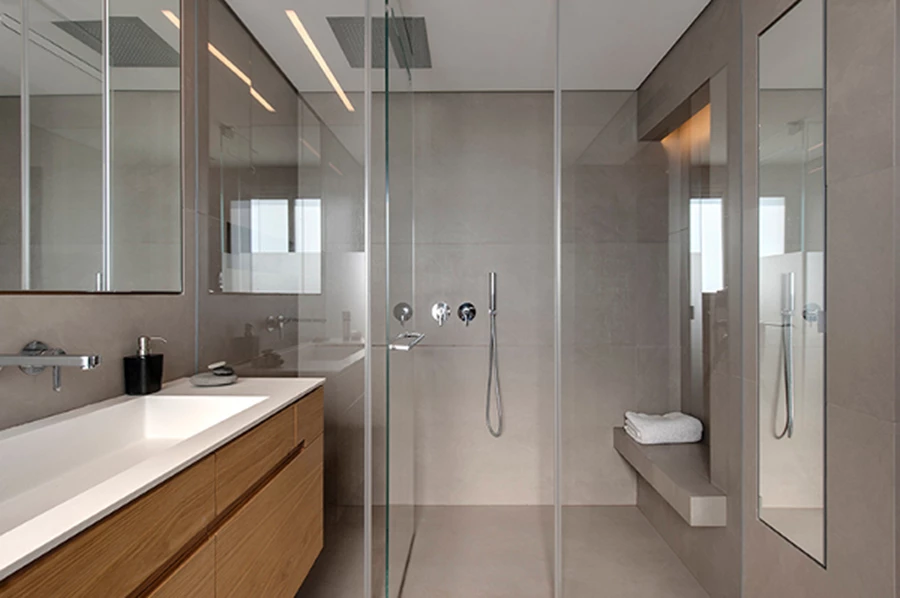 חדר רחצה בקווים נקיים. המקלחון המרווח מחופה בלוחות בטון. שידת הנגרות ונישות האחסון הנבלעות בקירות תוכננו במיוחד, להעניק חום טבעי ושימושיות לחלל (צילום: עודד סמדר).