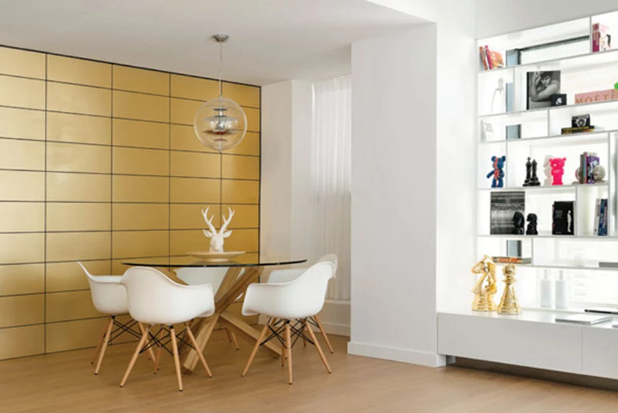 פינת האוכל הסמוכה לקיר הזהב בעיצוב מסוגנן-מאופק המותיר לו את קדמת הבמה: שולחן עגול עם בסיס עץ קליל ומשטח זכוכית, כיסאות אייקוניים של אימס, וגוף תאורה אייקוני שעיצב ורנר פנטון בשנות החמישים.