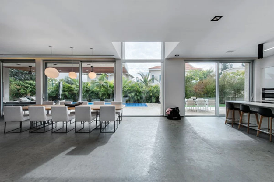 מבט חזיתי מדלת הכניסה: שקיפות מלאה לגינה ואזור של חלל כפול בין המטבח ופינת האוכל. גוף תאורה פ.אוכל: 